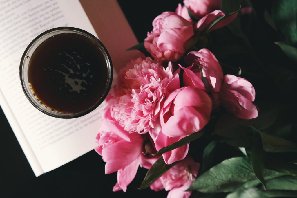 pink flowers beside cup on book